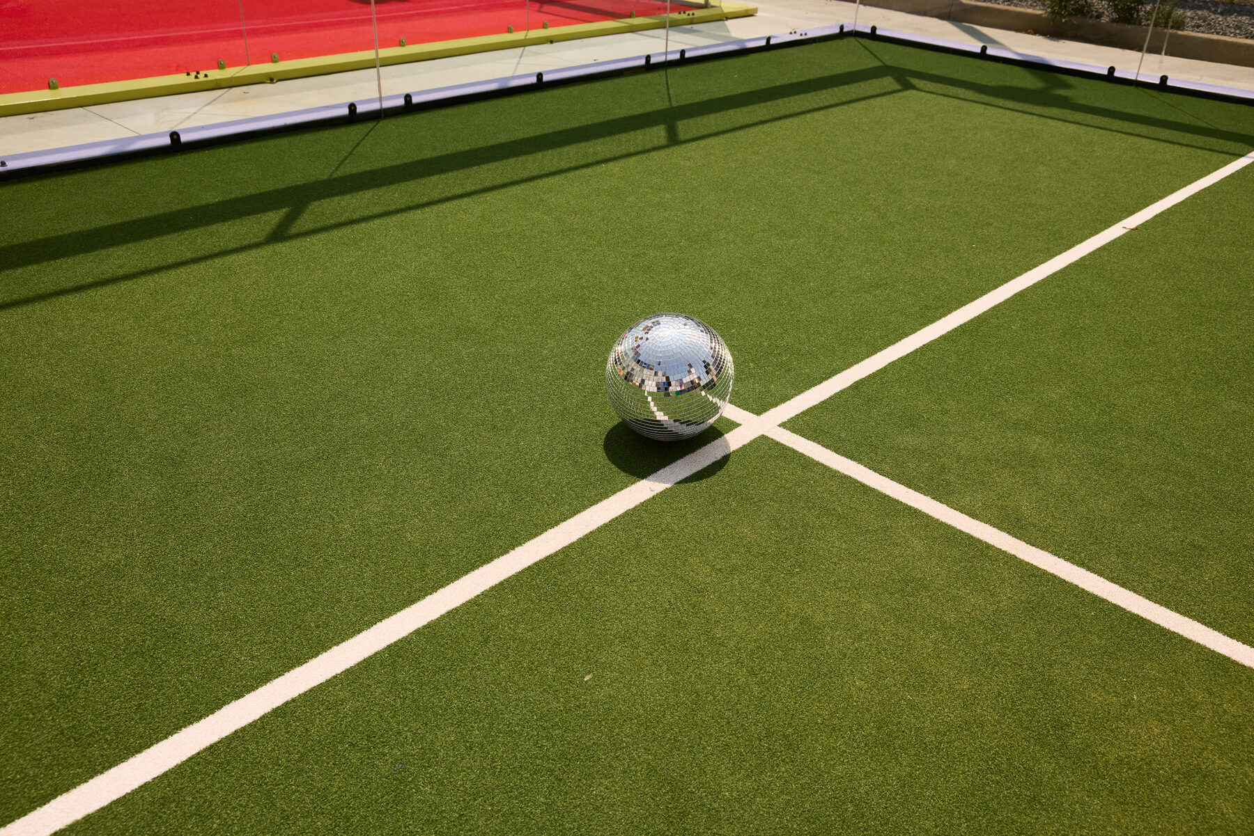 A disco ball resting on a green Fairgrounds court