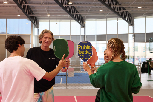 Four players meet paddles over the net at a Fairgrounds court