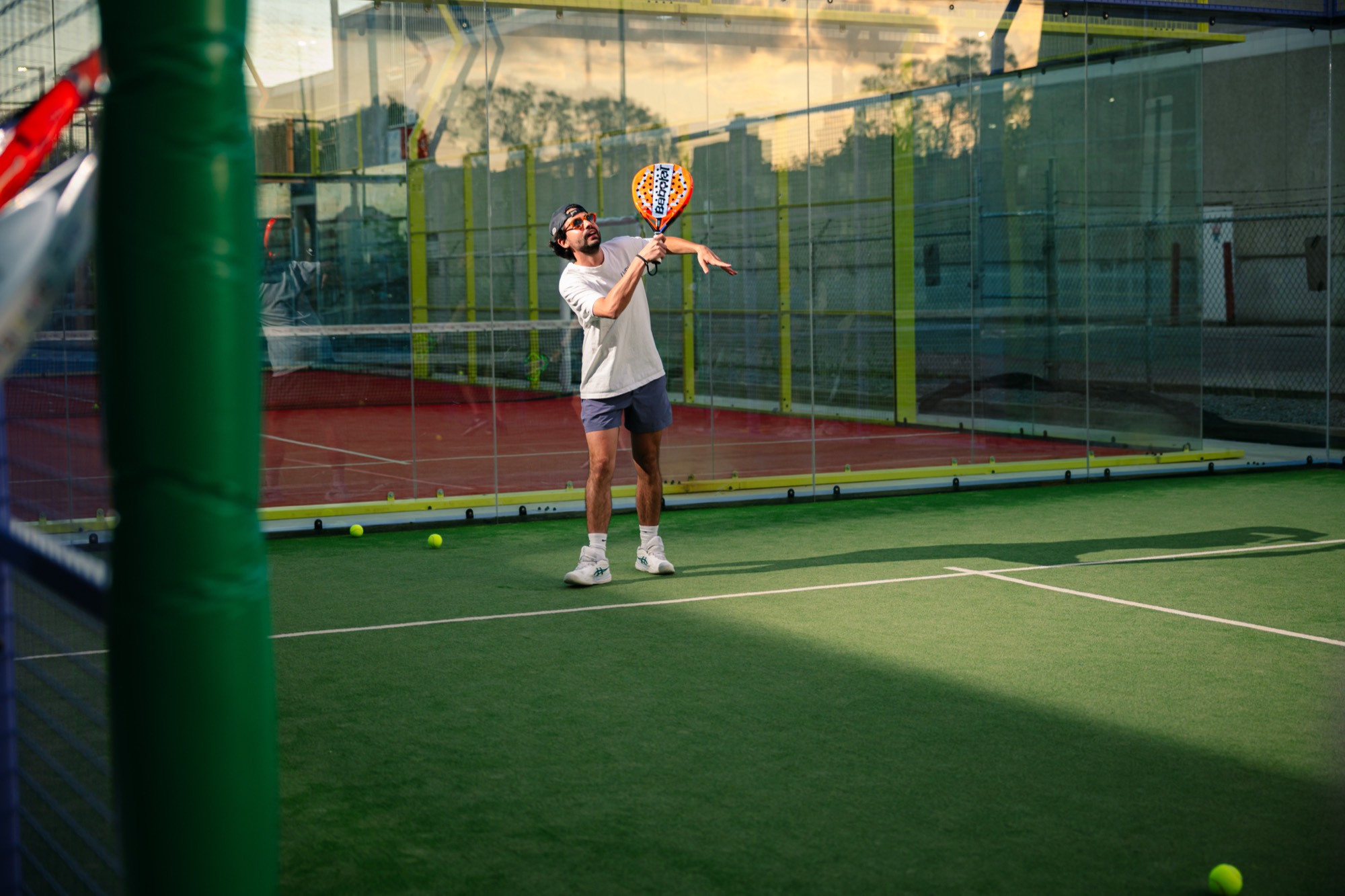 A player serves on a Fairgrounds padel court at sunset