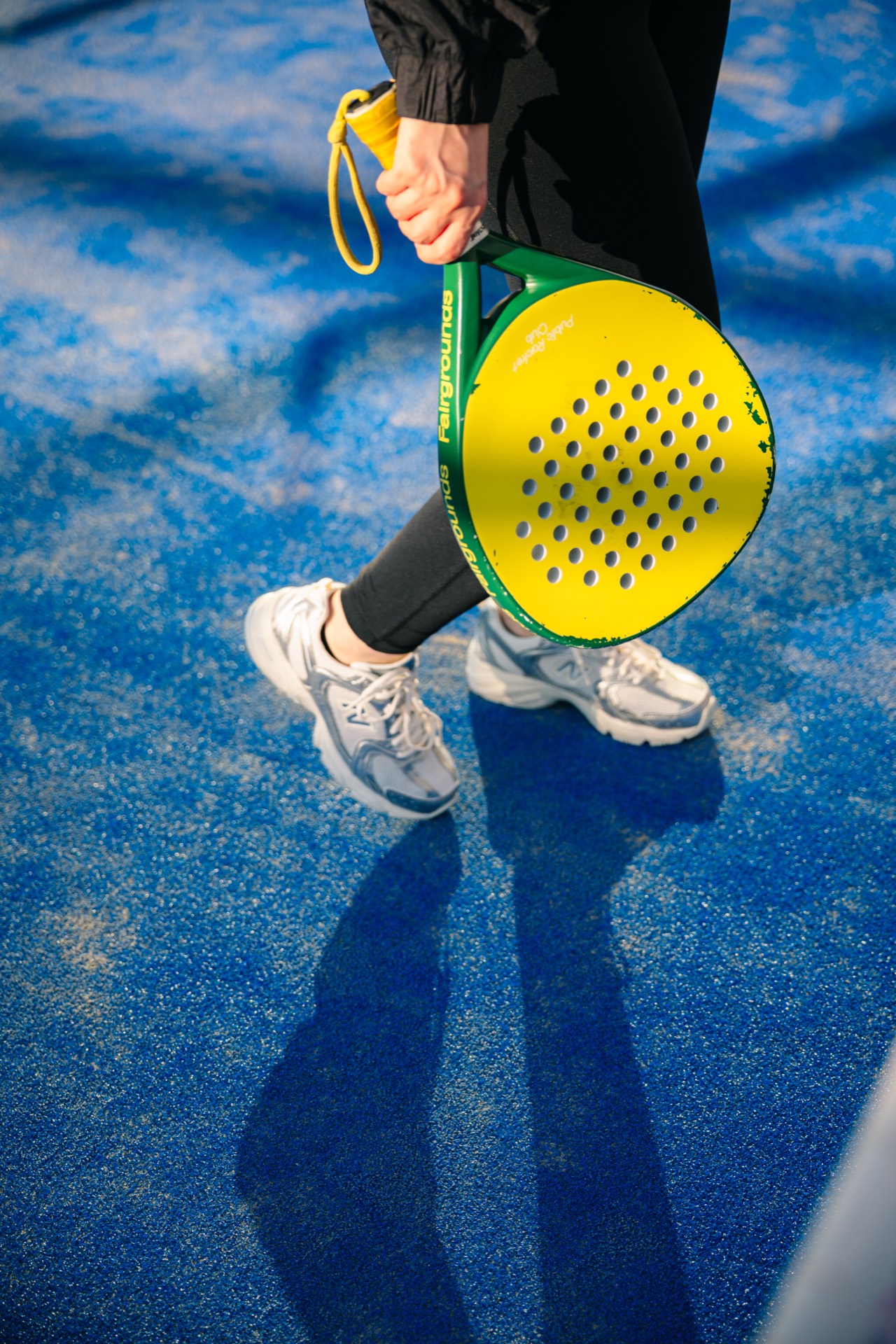 A player carries a Fairgrounds paddle across a blue court